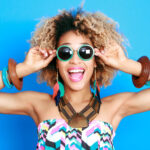curly-haired woman smiles with sunglasses after professional teeth whitening in Broken Arrow, OK