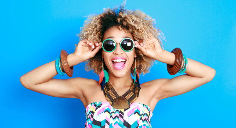 curly-haired woman smiles with sunglasses after professional teeth whitening in Broken Arrow, OK