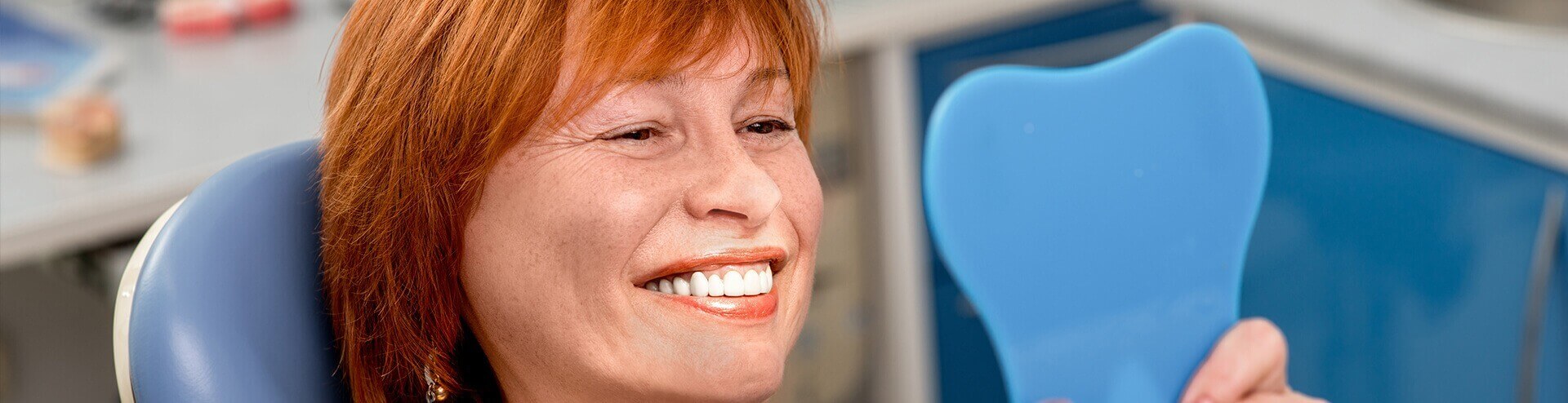 woman examining her dentures in a mirror