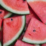 Aerial view of watermelon slices with a green and white rind, pink flesh, and black seeds