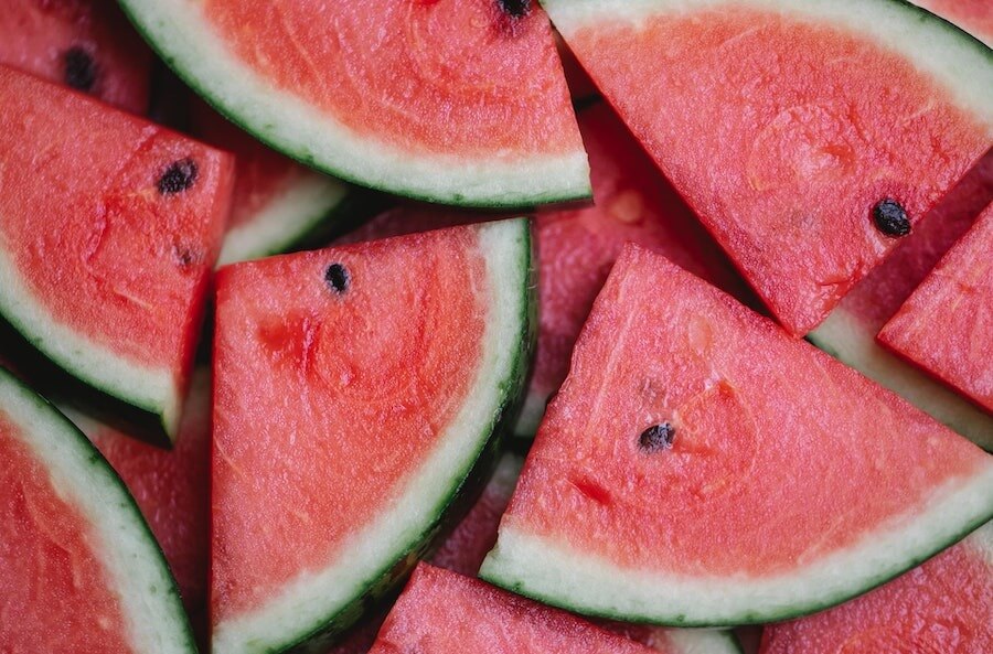 Aerial view of watermelon slices with a green and white rind, pink flesh, and black seeds