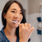 Asian woman brushing her teeth and following tips for a healthy smile